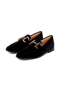 Par de mocasines de terciopelo negro con detalle de hebilla de metal dorado y suelas bajas negras, exhibidos sobre fondo blanco.