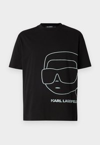 Black cotton t-shirt featuring a large white outline graphic of a face with sunglasses, and the text "KARL LAGERFELD" at the bottom.