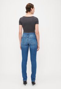 Visoke modre jeans hlače z gladkim tekstilom in rahlo zbledelostjo, v kombinaciji z oprijetim temnosivim majico s kratkimi rokavi.