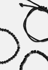 Juodų papuošalų rinkinys, kuriame yra du karoliukų apyrankės su apvaliais ir kubiniais karoliukais, taip pat pintas virvės akcentas. Visi elementai yra juodi su metaliniais akcentais.