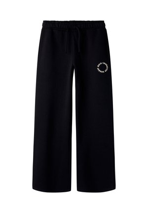 Pantalon de survêtement noir à jambes larges avec taille élastique et cordon, comportant un petit logo texte circulaire blanc sur le haut de la cuisse gauche.