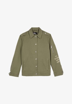 Veste vert olive en coton robuste. Elle présente des boutons-pression, des épaulettes, une poche zippée et du texte imprimé sur la manche.