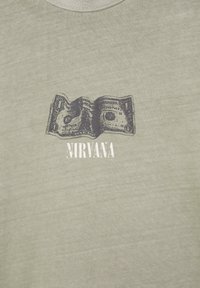 Haalistunut oliivinvihreä paita, jossa mustavalkoinen kuva taitetusta dollarin setelistä valkoisen Nirvana-sanan yläpuolella sapluunakirjaimilla.