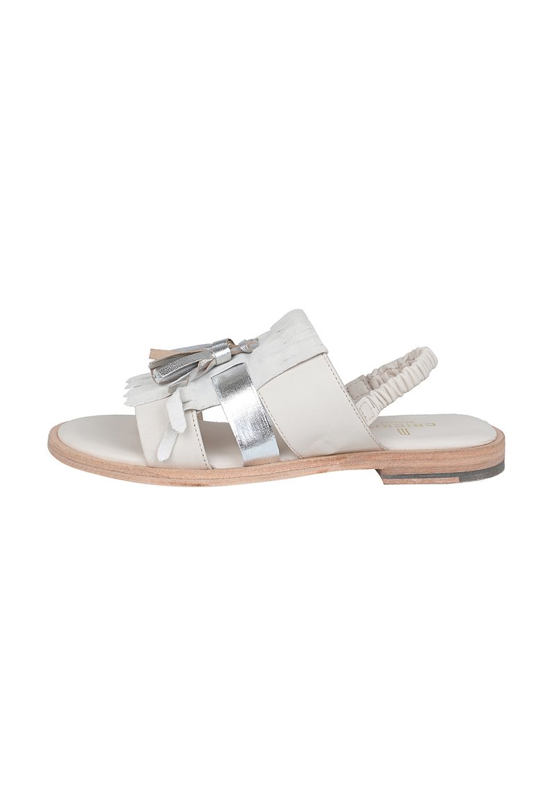 Sandal light beige con accenti metallici argento, dettagli in frange e una fascia posteriore imbottita. Suola piatta in legno con una finitura liscia.