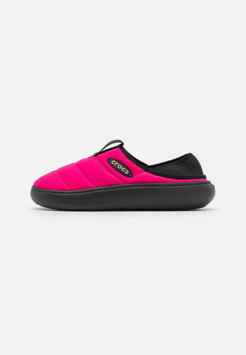 Sapatilha slip-on acolchoada rosa com sola e detalhes pretos. Apresenta um logótipo e um design elegante, adequada para uso casual.