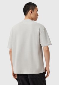 Jasnoszara krótki rękaw t-shirt o luźnym kroju, okrągłym dekolcie i gładkiej fakturze. Minimalistyczny design bez widocznych logo lub wzorów.
