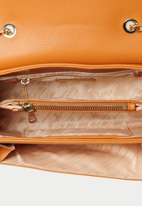 Borsa arancione con esterno testurizzato, hardware dorato e un ampio interno dotato di una tasca con zip e fodera a fantasia.