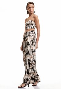 Ensemble deux pièces comprenant un top court sans bretelles et un pantalon ample dans un motif tie-dye noir, beige et marron. Fabriqué en tissu doux.