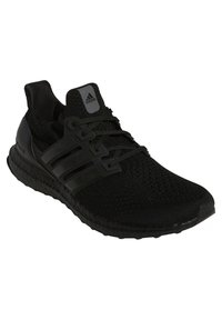 Chaussure de sport noire avec une tige en maille, des lacets noirs assortis, trois bandes rayées et une semelle en caoutchouc texturée.