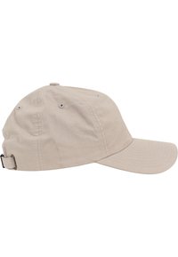 Beige honkbalpet met een gebogen rand, gemaakt van stof, voorzien van ventilatieopeningen en een verstelbare strap aan de achterkant.
