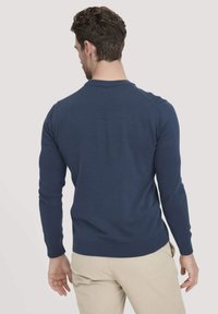 Navy-blau gestrickter Pullover mit langen Ärmeln, geripptem Kragen und Saum, körpernahem Design und glatter Textur. Sichtbare Nahtdetails an den Schultern.