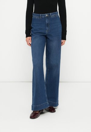 Jeans de ganga azuis de cintura alta com um corte amplo, apresentando um fecho frontal de botão e detalhes de costura clássicos. Textura suave.