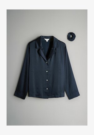 Tumši zilas pogāmo krekls ar baltiem punktiņiem, satīna tekstūra, garām piedurknēm un iegriezta apkakle, kopā ar saskaņotu scrunchie.