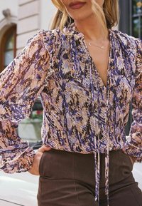 Langærmet bluse i et multicolor slangeprint, med V-udskæring, flæseærmer og bånddetalje, lavet af letvægtsmateriale.