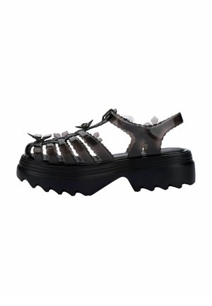 Sandales à plateforme épaisses noires avec design découpé, bride ajustable et semelle texturée. Fabriquées en matériau brillant avec des accents floraux.