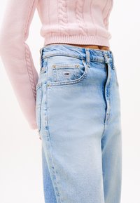 Light blue high-waisted jeans with a slightly faded texture, featuring gold hardware and a small brand logo on the pocket.