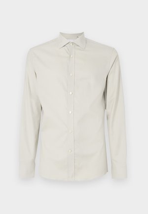 Gai krēmkrāsas, garām piedurknēm, krekls, izgatavots no gludas auduma, ar norādītu apkakli, priekšpuses pogu aizdari un bez redzamām rakstām vai akcentiem.