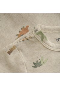 Ljus beige tygskjorta med färgglada dinosaurie- och växttryck, med ribbat halsband och tryckknappar för enkel påklädning.