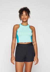 Lys blå crop top med mørkeblå detaljer, med en tettsittende design. Kombinert med svarte, lette shorts for aktivt bruk.