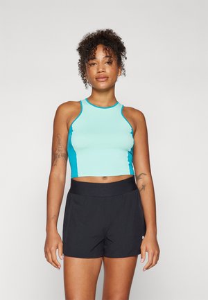 Lys blå crop top med mørkeblå detaljer, med en tettsittende design. Kombinert med svarte, lette shorts for aktivt bruk.