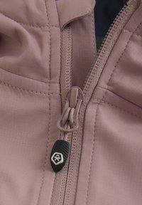 Rosa tyg med strukturerad yta och synliga stygn, med en dragkedja och en svart gummihandtag samt hexagonalt logotypdetalj.