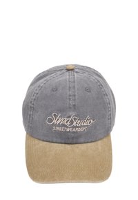 Șapcă din țesătură gri cu o vizieră din suede bej. Prezintă text brodat în maro deschis și o curea ajustabilă în spate.