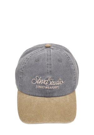 Casquette en tissu gris avec une visière en suède beige. Présente un texte brodé en brun clair, avec une sangle ajustable à l'arrière.