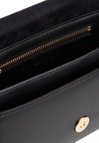 Μαύρο πορτοφόλι κατασκευασμένο από λείο δέρμα και απαλό σουέντ, με χρυσό φερμουάρ και κούμπωμα με κουμπί. Το εσωτερικό περιλαμβάνει πολλαπλές θήκες για κάρτες.