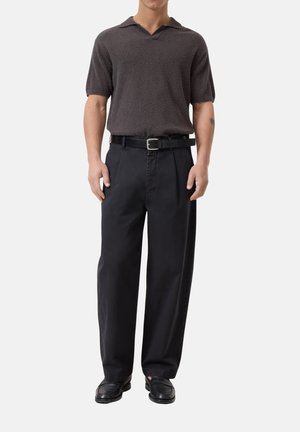 Polo a maniche corte, marrone scuro, con texture e scollo a V, abbinato a pantaloni neri a vita alta e gamba larga, con una cintura nera.