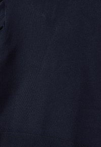 Marineblauer Strickstoff mit glatter Textur und geripptem Saum. Das Design ist einfach, ohne sichtbare Muster oder Verzierungen.