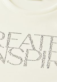 White short-sleeve shirt featuring "CREATE INSPIRE" in silver rhinestones, smooth texture, and round neckline.