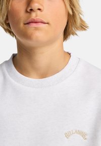 Felpa bianca con collo a costine, caratterizzata da un piccolo logo ricamato color marrone chiaro sul petto. Texture morbida e design informale.