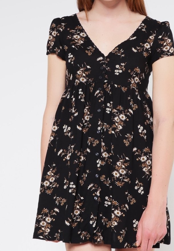 Czarna sukienka w kwiaty z krótkimi rękawami, dekoltem w kształcie litery V oraz zapięciem na guziki z przodu. Tkanina ma miękką teksturę z wzorami białych i brązowych kwiatów.