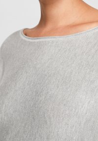 Šedý pletený top s širokým výstřihem, hladkou strukturou a krátkými rukávy. Materiál vypadá měkce a pohodlně.