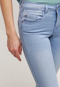 Ljusblå denimjeans med slim fit, med fem fickor, en midja med bälteshällor och kontrasterande sömmar.