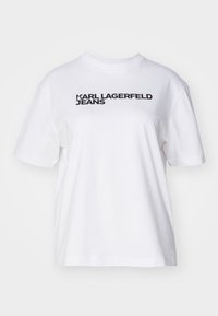 Camiseta de algodón blanca con un corte relajado. Presenta la impresión "KARL LAGERFELD JEANS" en texto negro en negrita a lo largo del pecho. Mangas cortas.