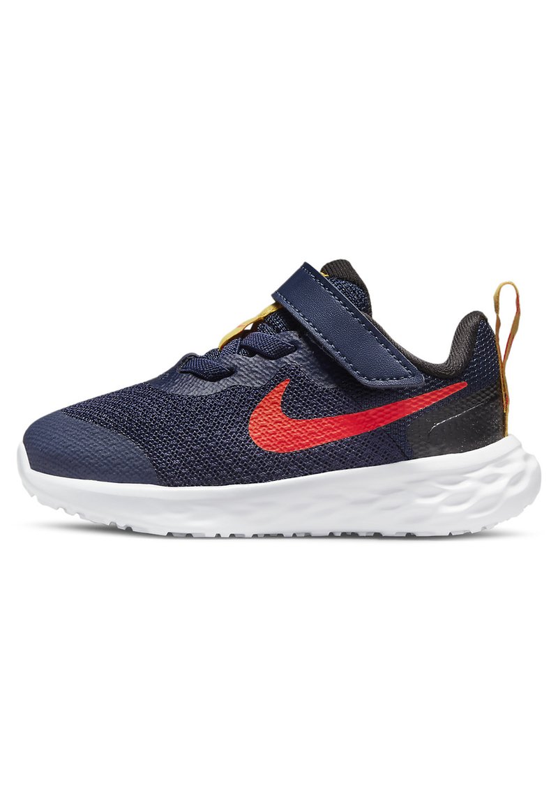 Mėlynos tinklinės sportinės bateliai su raudonu Nike ženklu, balta pado dalimi ir Velcro juosta. Yra geltonos raištelės ir kilpa ant kulno.