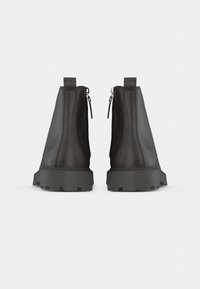 Svarta läderstövlar vid ankeln med matt yta, sidodragkedjor och slitstarka gummisulor. Har en rund tå och förstärkt sömnad.