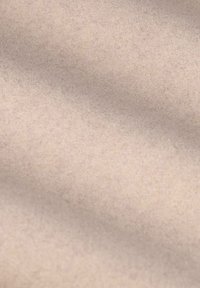 Tissu beige clair avec une surface douce et texturée, présentant des variations subtiles de ton et une finition lisse. Idéal pour le rembourrage ou les accessoires.