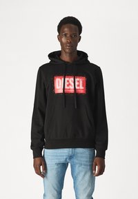 Black hoodie with a front kangaroo pocket, featuring a red ‘DIESEL’ logo print. Drawstrings on the hood. Soft cotton material.