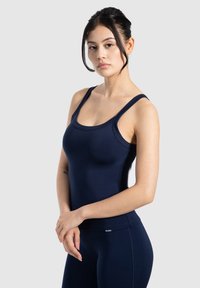 Marineblauw sporttop met een aansluitend ontwerp, ronde halslijn en brede banden, gemaakt van glad, rekbaar stof. Minimale merkdetails.