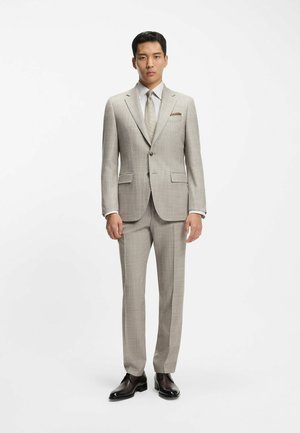 Light beige suit with a subtle check pattern, featuring a notch lapel, two front pockets, and a matching tie. Complemented by dark shoes.