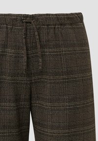 Bruine geruite broek met een elastische tailleband en trekkoord. De textuurstof heeft afwisselende lichte en donkere strepen van verschillende diktes.
