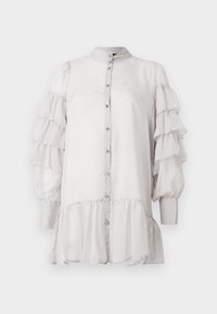 Vaaleanharmaa pusero, jossa on röyhelöityjä läpikuultavia hihoja, mandarinkaulus, napillinen edusta ja kerroksittain ulottuva helma. Sileä pinta, pehmeä viimeistely.