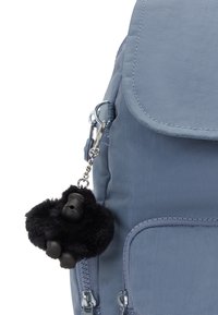 Ljusblå ryggsäck med frontficka och en svart fluffig gorillanyckelring fäst vid dragkedjan.