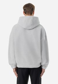 Grauer Fleece-Hoodie mit großer Kapuze, überschnittenen Schultern und geripptem Saum. Weicher Stoff und lässige Passform für hohen Tragekomfort.
