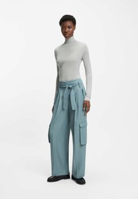 Light gray turtleneck top paired with wide, high-waisted slate blue cargo pants featuring a tied waist, pleats, and side pockets.