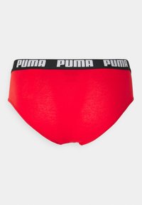 Rote Baumwollslips mit einem schwarzen Gummibund, der das weiße "PUMA"-Logo zeigt. Weicher Stoff, Standardschnitt, nahtloses Rückenteil.