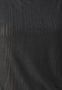 Tissu noir côtelé avec des lignes verticales, présentant une texture légèrement transparente. Le matériau semble extensible et doux. Pas de motifs ni de pièces métalliques visibles.