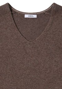 Brązowy sweter z dekoltem w serek, o gładkiej fakturze, wykonany z dzianiny. Metka wskazuje "CECiL". Brak zauważalnych wzorów lub akcentów.